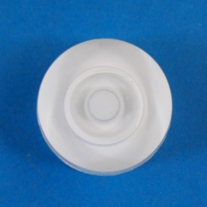 May include: White plastic bottle cap with a concentric circle design.