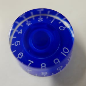 May include: A blue plastic knob with white numbers 1 through 10 printed around the edge.
