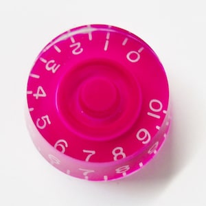 May include: A bright pink guitar knob with white numbers 0-10 around the edge.