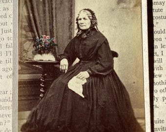Fotografía antigua tipo tarjeta de visita: viuda de luto con pañuelo y flores coloreadas a mano.