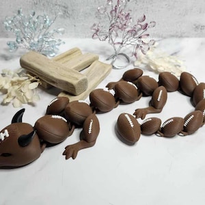 May include: A brown dragon sculpture made of footballs with white stitching. The dragon has horns and arms. Decorative elements include wooden blocks and floral accents.