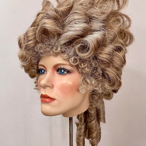 K&ouml;nnte beinhalten: Eine blonde Per&uuml;cke mit gro&szlig;en Locken und einem langen, gelockten Pferdeschwanz. Die Per&uuml;cke ist in einem klassischen, eleganten Stil gestylt.