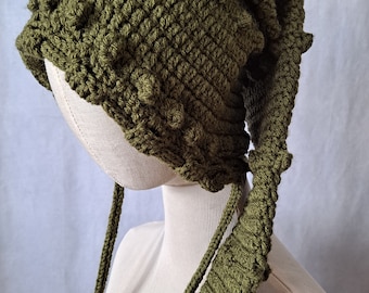 May include: A green crocheted hat with a long, pointed tail. The hat has a textured surface and is made with a chunky yarn.