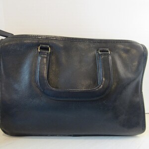 May include: A black leather satchel bag with two top handles and a zipper closure.
