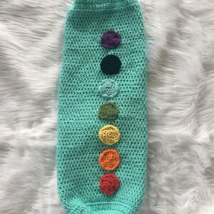 May include: A turquoise crocheted baby sleeping bag with colorful crocheted circles down the front.