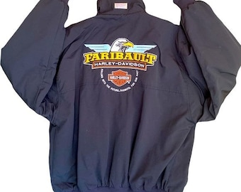 May include: Black bomber jacket with a large embroidered patch on the back. The patch features a bald eagle with wings spread, the words "Faribault Harley-Davidson", and a Harley-Davidson logo. The text "Rolling into the future, thanks for the ride" is also on the patch.