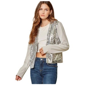 Puede incluir: Una chaqueta plateada con lentejuelas, mangas largas y un dobladillo recortado. La chaqueta está hecha de una tela suave y cómoda y tiene un ajuste holgado.