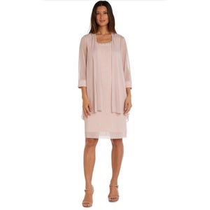 May include: A pale pink dress and jacket ensemble. The dress features a scoop neckline with a beaded detail. The jacket has three-quarter length sleeves and a flowing silhouette. The outfit is completed with light pink heels.