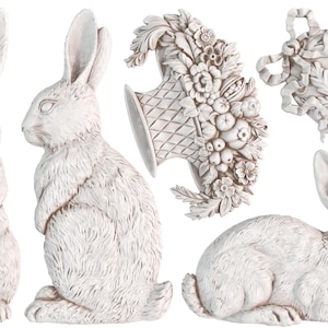 May include: A collection of white rabbit figurines and decorative wall art. The rabbits are in various poses, including standing, sitting, and reclining. The wall art includes a basket of flowers and a decorative oval piece.