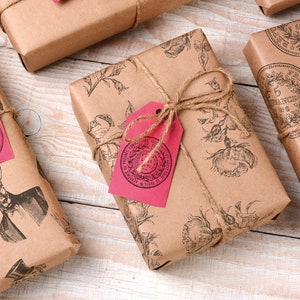 May include: Several wrapped gifts with brown paper and twine. The paper is printed with various designs, including deer, floral patterns, and coin illustrations. Each gift has a pink tag tied with twine.
