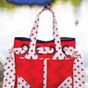 May include: Red tote bag with white polka dot fabric accents and a blue and white polka dot ribbon. The bag has a large pocket on the front and the text "Bon Voyage" is printed on the front of the bag.
