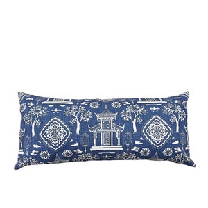 May include: A long, rectangular decorative pillow with a blue and white Asian-inspired pattern. The design features pagodas, trees, and floral motifs. The pillow is approximately 30 inches long.