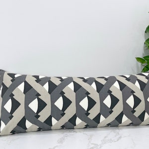 May include: A long, rectangular pillow with a geometric pattern in shades of gray and white. The pillow is made of a soft, woven fabric and has a subtle sheen.