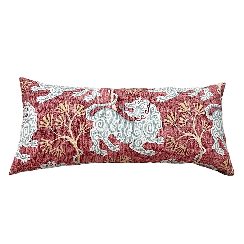 May include: A red lumbar pillow with a white and blue patterned design featuring stylised lions and trees.