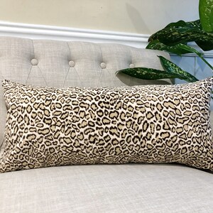 May include: A beige and brown leopard print lumbar cushion on a light beige sofa.