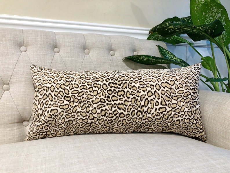 May include: A beige and brown leopard print lumbar cushion on a light beige sofa.