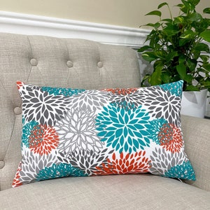 May include: Teal, gray, and orange floral patterned throw pillow. The pillow is rectangular and has a white background.