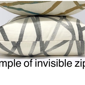 May include: Close-up of a white cushion with a grey and black geometric pattern. The cushion has an invisible zipper on the bottom edge. "Example of invisible zipper" is written below the cushion.
