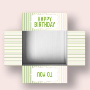 Könnte beinhalten: Eine offene Geburtstagsgeschenkbox mit weißem Innenraum. Die Außenseite hat ein grün-weißes Streifenmuster. Auf der oberen Klappe steht "HAPPY BIRTHDAY" in grüner Schrift, und auf der unteren Klappe steht "TO YOU".