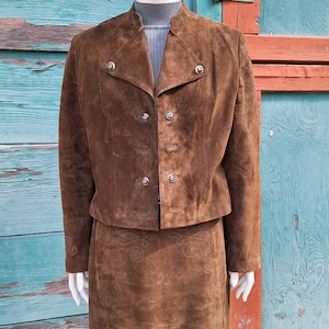 A brown suede skirt suit with a short matching jacket and a skirt with an embroidered design.