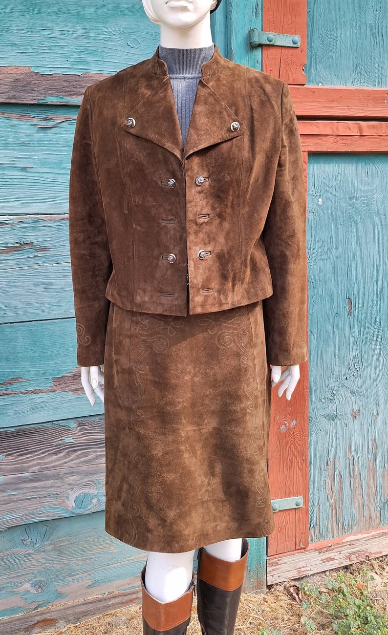 A brown suede skirt suit with a short matching jacket and a skirt with an embroidered design.