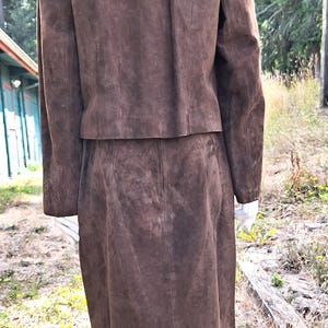 Back view of a brown suede skirt suit with a matching jacket and skirt. The skirt is knee-length and the jacket has a collarless neckline.