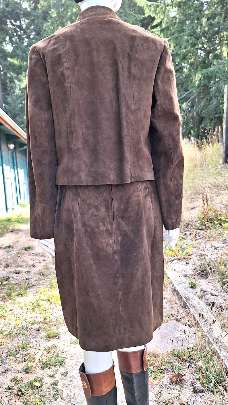 Back view of a brown suede skirt suit with a matching jacket and skirt. The skirt is knee-length and the jacket has a collarless neckline.
