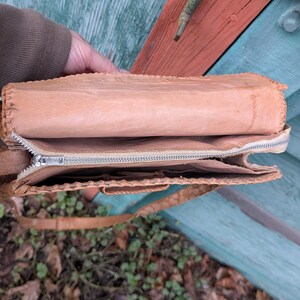 Top down view of the inside of a structured snakeskin purse. The inside lining is light beige leather with a zippered center and pouches on either side