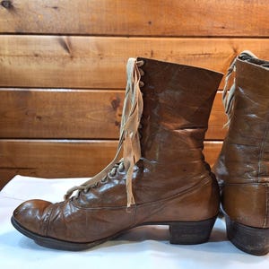 side image of a pair of ladies brown leather Victorian boots with light tan laces and rounded toes. The boots have a medium heel and are low-calf in height.