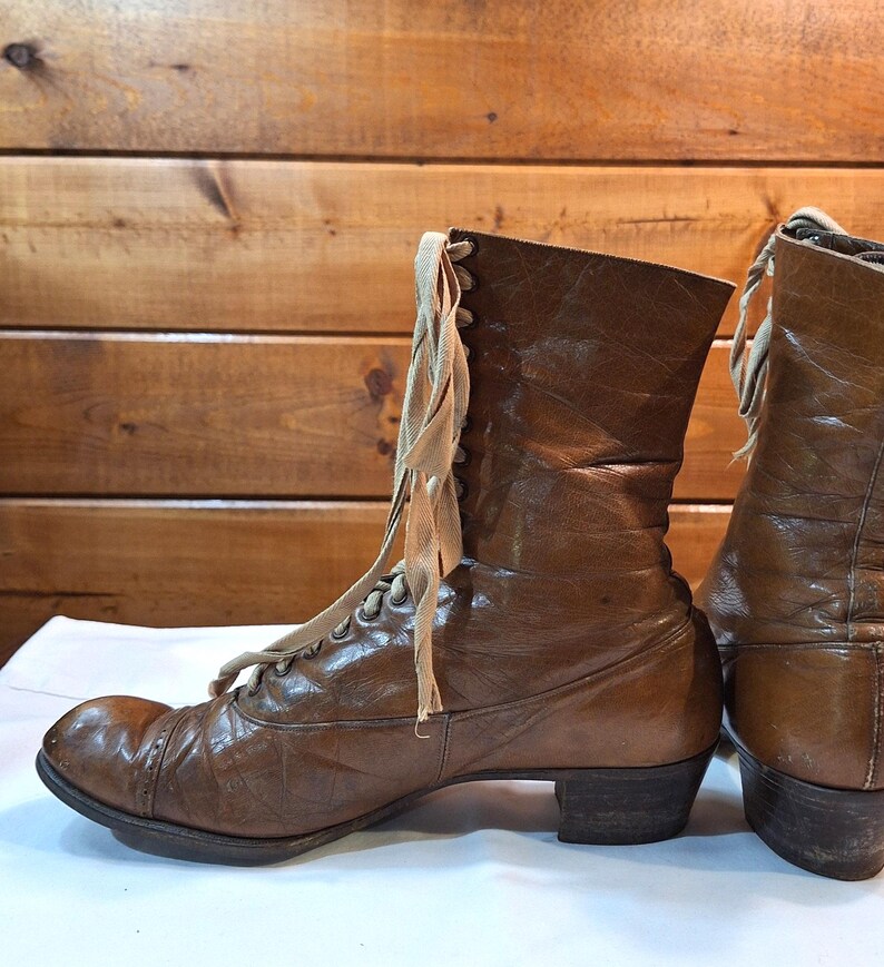 side image of a pair of ladies brown leather Victorian boots with light tan laces and rounded toes. The boots have a medium heel and are low-calf in height.