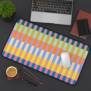 May include: A colorful desk mat with a geometric pattern of pink, blue, yellow, green, and orange squares. A white computer mouse is on the mat.