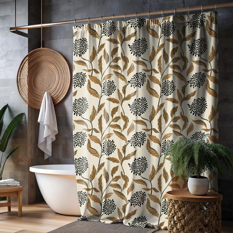 May include: Cream-colored shower curtain with a repeating pattern of brown leaves and black, dotted floral clusters. The curtain hangs in front of a white bathtub, with a woven basket and a small wooden stool visible in the background.
