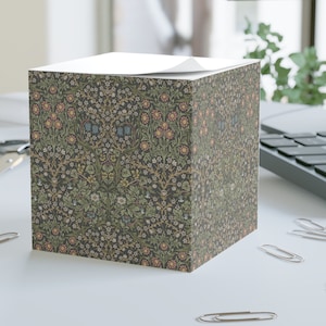 Könnte beinhalten: Ein quadratischer Notizblock mit einem floralen Muster in Grün-, Rosa-, Blau- und Gelbtönen. Das Muster erinnert an ein Vintage-Tapetenmuster.