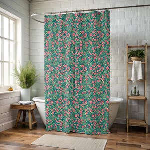 May include: Teal shower curtain with a repeating floral pattern of pink flowers and green leaves. The curtain hangs in front of a white bathtub, with a wooden stool and a window visible in the background. The curtain is made of a soft, durable material.