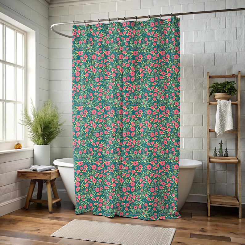 May include: Teal shower curtain with a repeating floral pattern of pink flowers and green leaves. The curtain hangs in front of a white bathtub, with a wooden stool and a window visible in the background. The curtain is made of a soft, durable material.