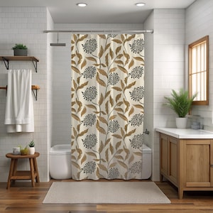 May include: A beige shower curtain with a repeating pattern of brown leaves and black, dotted floral clusters. The curtain hangs in a bathroom with white tile walls, a wooden vanity, and a small wooden stool.