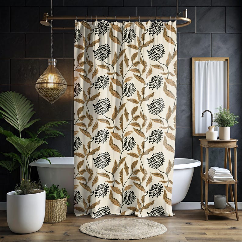 May include: Cream-colored shower curtain with a repeating pattern of brown leaves and black dotted flower clusters. The curtain hangs in front of a white bathtub, with a gold shower rod. The bathroom has dark tile walls and a wooden floor.