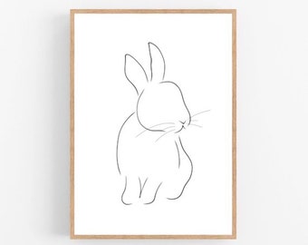 May include: A minimalist line drawing of a rabbit in a wooden frame. The artwork features a simple, continuous black line that forms the outline of the rabbit against a white background. The rabbit is depicted in a seated position, with its ears upright and whiskers visible.