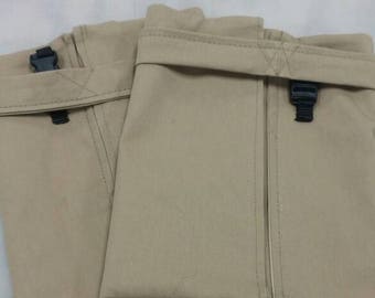 May include: Two tan fabric pouches with black buckles and a folded flap closure. The pouches are made of a sturdy material and are shown with a yellow measuring tape. The pouches are likely for storage or carrying items.