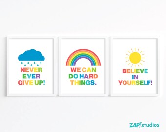 May include: Three framed art prints with motivational quotes. The first features a blue cloud with rain and the text "NEVER EVER GIVE UP!". The second shows a rainbow and the text "WE CAN DO HARD THINGS.". The third has a yellow sun and the text "BELIEVE IN YOURSELF!"