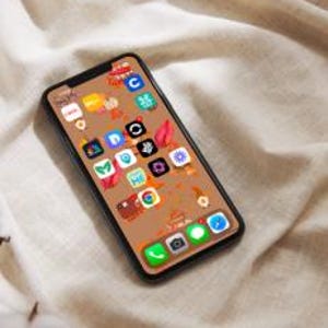 May include: A smartphone with a brown background and a variety of app icons on the screen. The icons are arranged in a grid pattern and include apps such as Instagram, TikTok, and Spotify.
