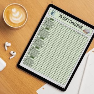 May include: A digital tablet displaying a green and white printable 75 Soft Challenge workout tracker. The tracker includes columns for the date, week, and days of the week. The tracker also includes a small illustration of a kettlebell.