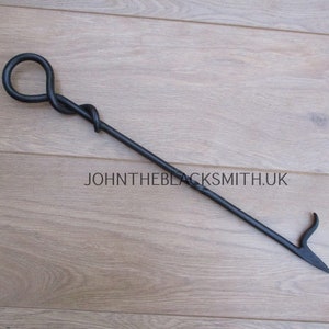 May include: Black metal fireplace poker with a twisted handle and a hook on the end.  The poker is on a wooden surface.  JOHNTHEBLACKSMITH.UK