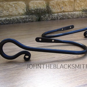 May include: Two black metal curtain tiebacks with a decorative swirl at the end.  The tiebacks are designed to hold curtains in place.