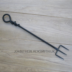 Könnte beinhalten: Schwarzer Kaminbesen aus Metall mit einem gedrehten Griff und einem dreizackigen Ende.