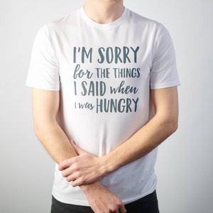 May include: White t-shirt with the text "I'm sorry for the things I said when I was hungry" printed in dark blue.