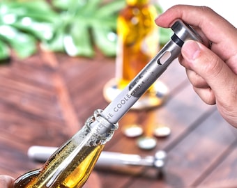 May include: A stainless steel bottle chiller with the text "Keep the Cooler" printed on it. The chiller is being inserted into the neck of a glass bottle of beer.