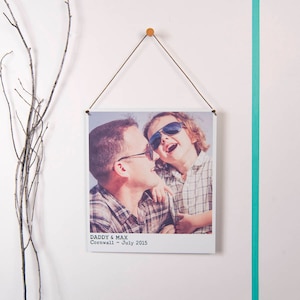 May include: A black and white photo of a father and son wearing sunglasses. The photo is printed on a white background with the text "Daddy & Max Cornwall - July 2015".