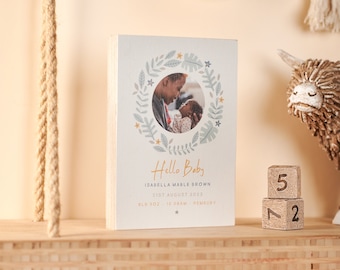 May include: A wooden block with a photo of a parent holding a baby in a leafy wreath. The text reads "Hello Baby", "Isabella Mable Brown", "21st August 2023", "8lb 8oz 10:06am Pembury".