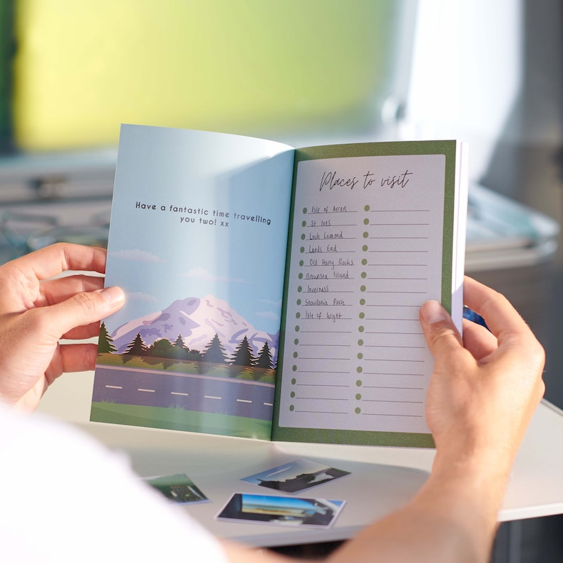 May include: A green travel journal with a checklist of places to visit. The journal has a mountain scene on the front cover with the text "Have a fantastic time travelling you two! xx".